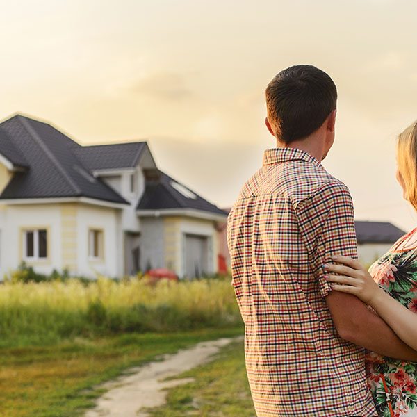 Couple embracing, looking at house
